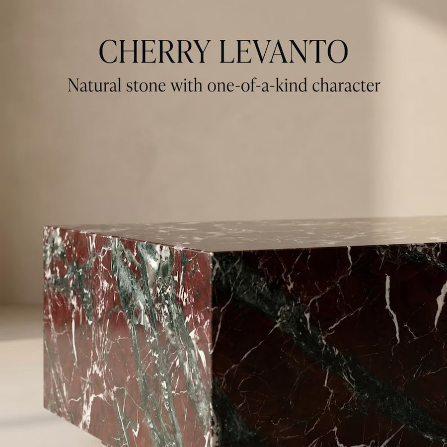 A polished stone slab or countertop section labeled 'CHERRY LEVANTO' with text reading 'Natural stone with one-of-a-kind character.' The stone has a deep reddish-brown base with prominent green and white veining, shown against a warm beige background.