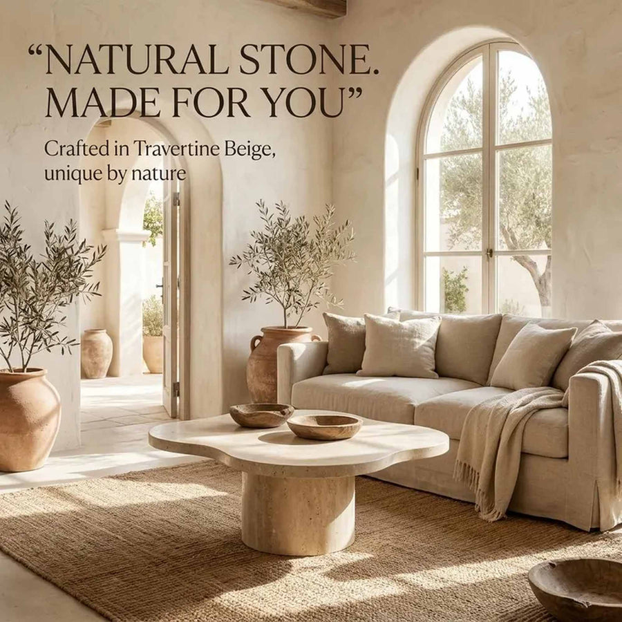 A styled interior scene showing a beige upholstered sofa, matching pillows, a round stone coffee table, and a large woven rug in a sunlit room with arched windows. Text on the left reads, “NATURAL STONE.