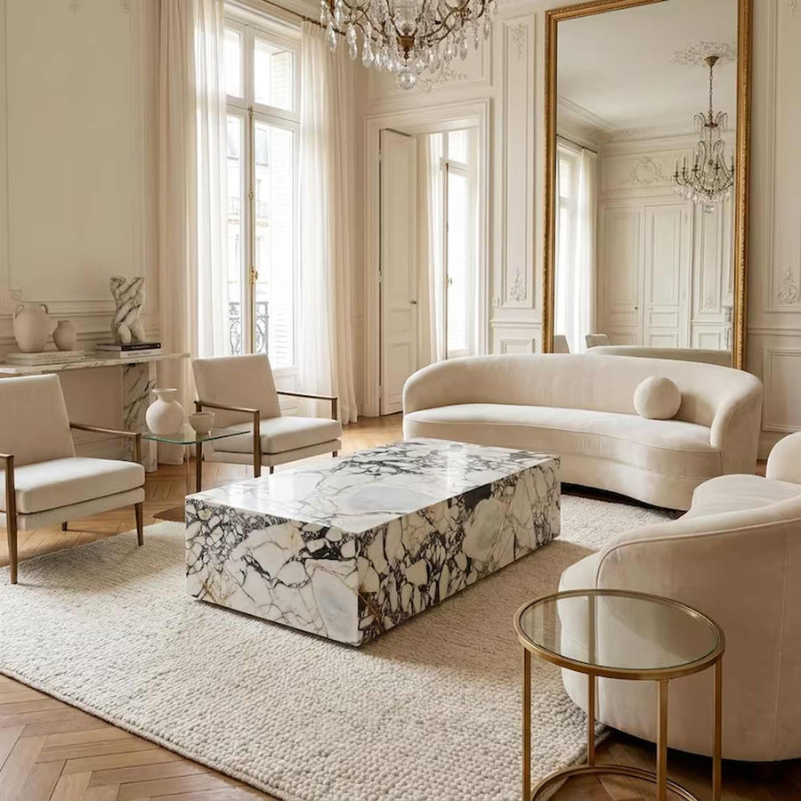 A luxury living room featuring a rectangular coffee table with a black and white veined marble top, styled in a classic French chaise design with cream velvet seating and gold accents.