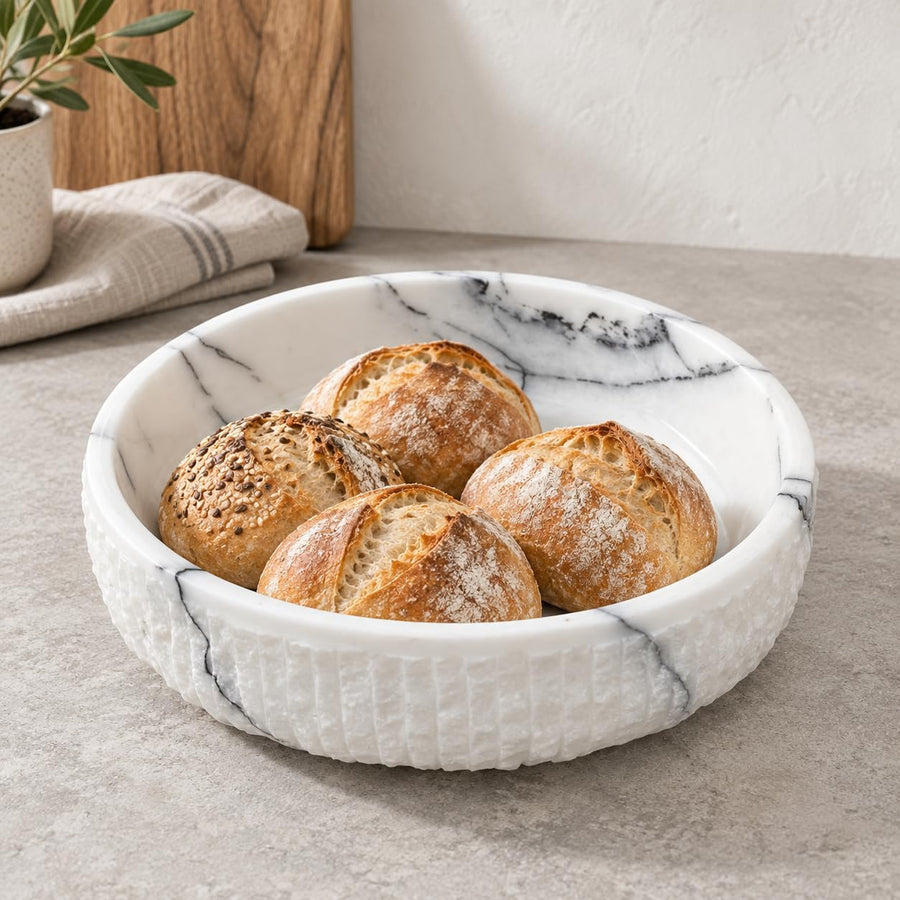 The Footed Lilac Marble Platter is a hand-carved natural stone platter raised on a foot, made from Lilac Marble. Its soft lilac veining and raised foot make it as pretty on a vanity as it is on a dessert table.