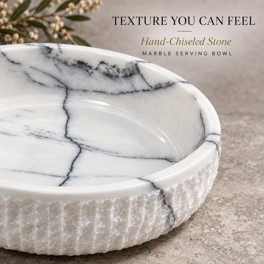 The Footed Lilac Marble Platter is a hand-carved natural stone platter raised on a foot, made from Lilac Marble. Its soft lilac veining and raised foot make it as pretty on a vanity as it is on a dessert table.