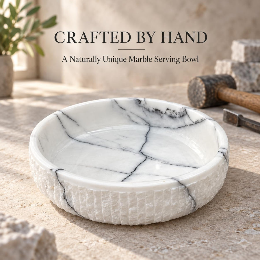 The Footed Lilac Marble Platter is a hand-carved natural stone platter raised on a foot, made from Lilac Marble. Its soft lilac veining and raised foot make it as pretty on a vanity as it is on a dessert table.