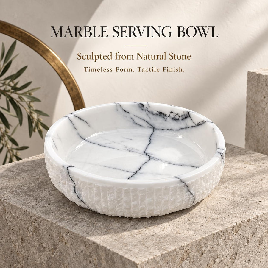 The Footed Lilac Marble Platter is a hand-carved natural stone platter raised on a foot, made from Lilac Marble. Its soft lilac veining and raised foot make it as pretty on a vanity as it is on a dessert table.