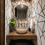 Bathroom with geometric wall design, round mirror, and stone sink.