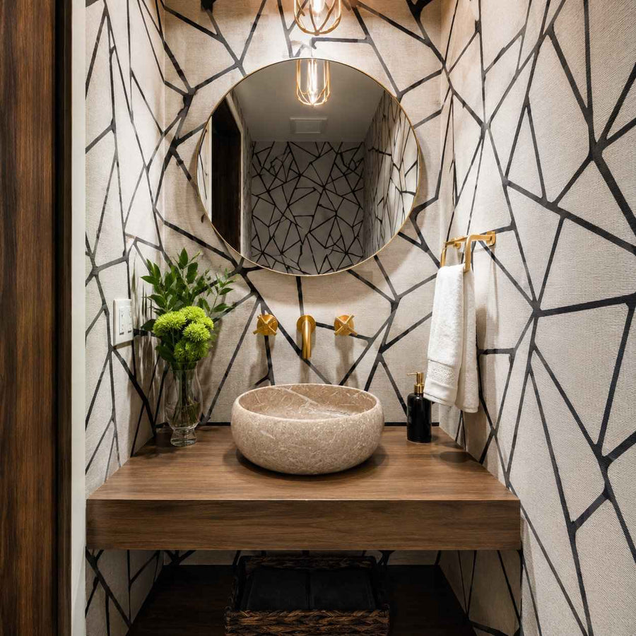 Bathroom with geometric wall design, round mirror, and stone sink.