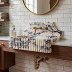 Marble-patterned sink with gold fixtures in a bathroom setting