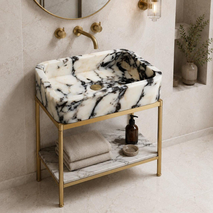 Black and white marble sink on a dark floating vanity with brass faucet in a moody bathroom