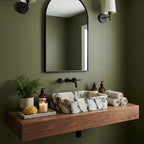 Black and white marble sink on a beige stone floating shelf under a round brass mirror