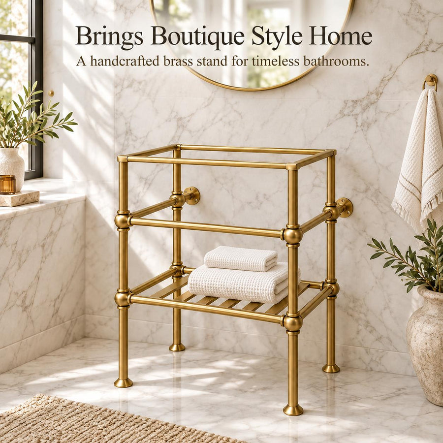 A brass bathroom stand with a two-tiered open frame design, styled in a bright marble bathroom with folded white towels on the lower shelf. Text at the top reads 'Brings Boutique Style Home - A handcrafted brass stand for timeless bathrooms.