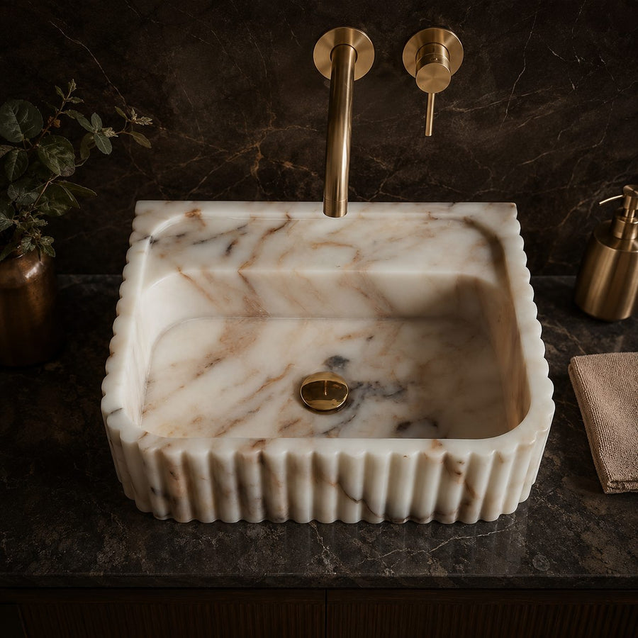 Top view of Calacatta Gold marble sink with scalloped fluted edge and brass faucet