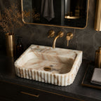 Top view of Calacatta Gold marble sink with scalloped fluted edge and brass faucet
