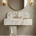 Bathroom sink with marble countertop, gold fixtures, and round mirror.