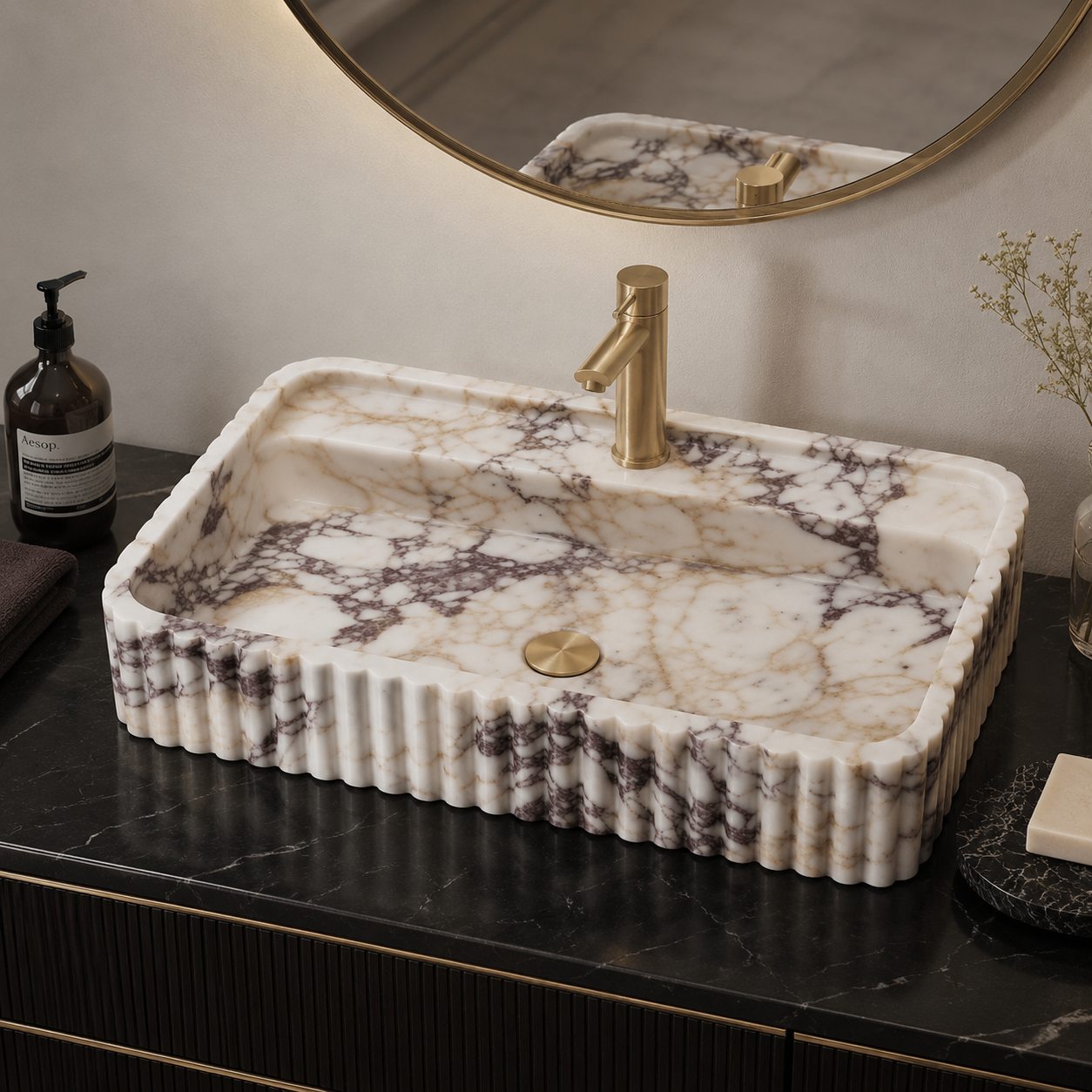 Calacatta Viola marble sink on a black marble countertop with brass faucet