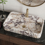 Calacatta Viola marble sink on a black marble countertop with brass faucet