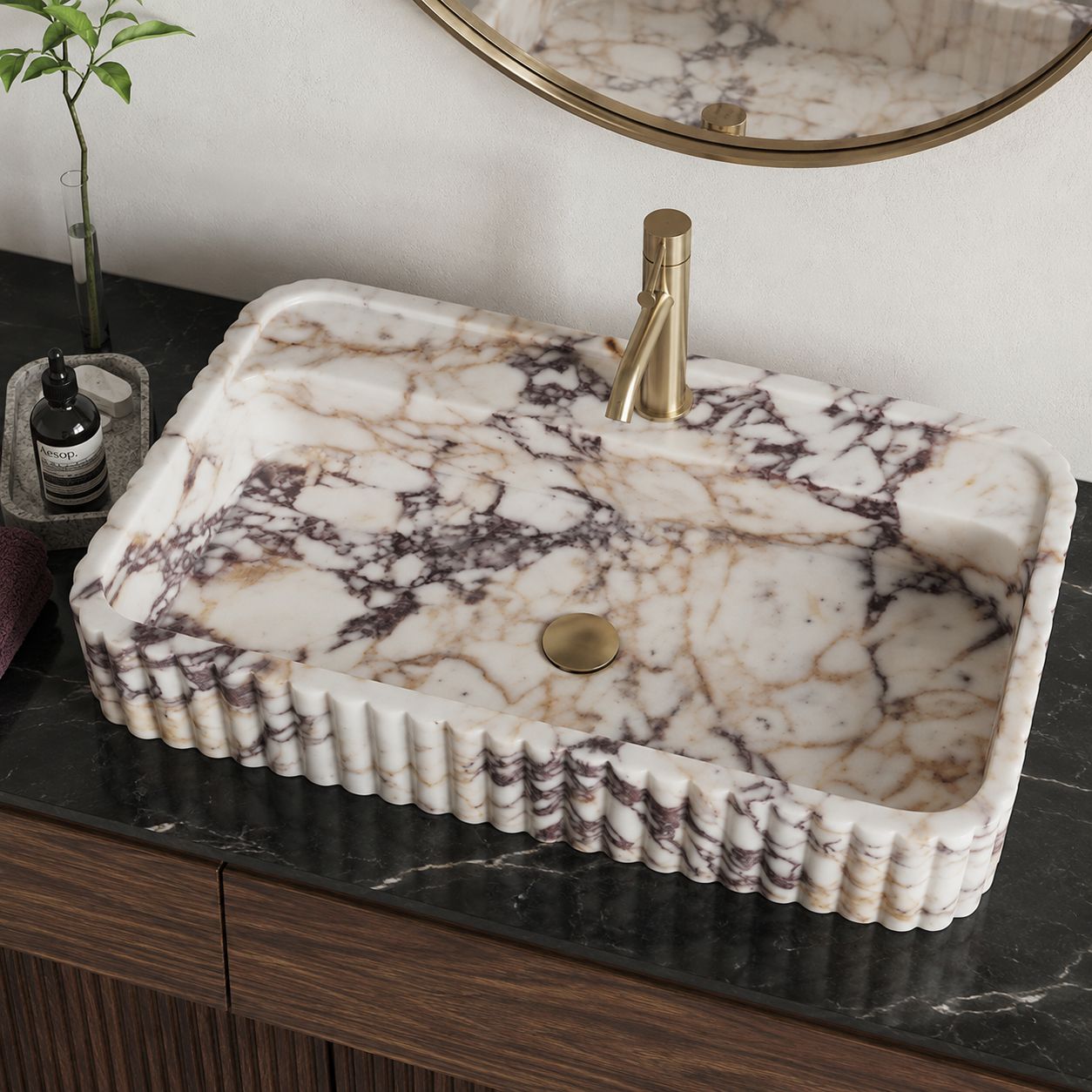 Calacatta Viola marble sink on a black marble countertop with brass faucet