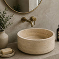 Bathroom with a stone sink, gold faucet, and decorative elements.