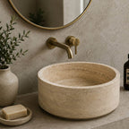 Bathroom with a stone sink, gold faucet, and decorative elements.