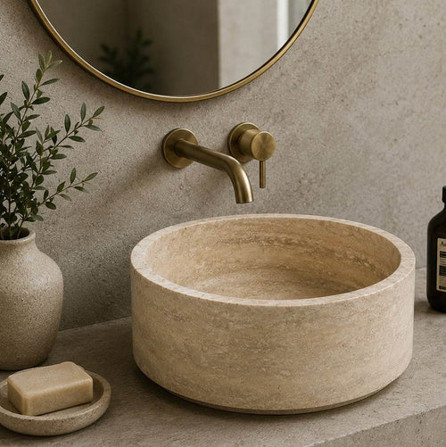 Bathroom with a stone sink, gold faucet, and decorative elements.