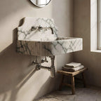 Wall-mounted marble sink with metallic fixtures in a bathroom setting.
