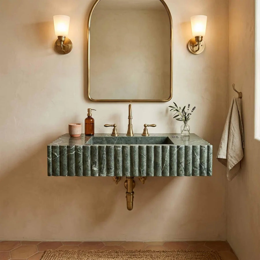 Bathroom vanity with green marble sink, gold fixtures, and wall lights.