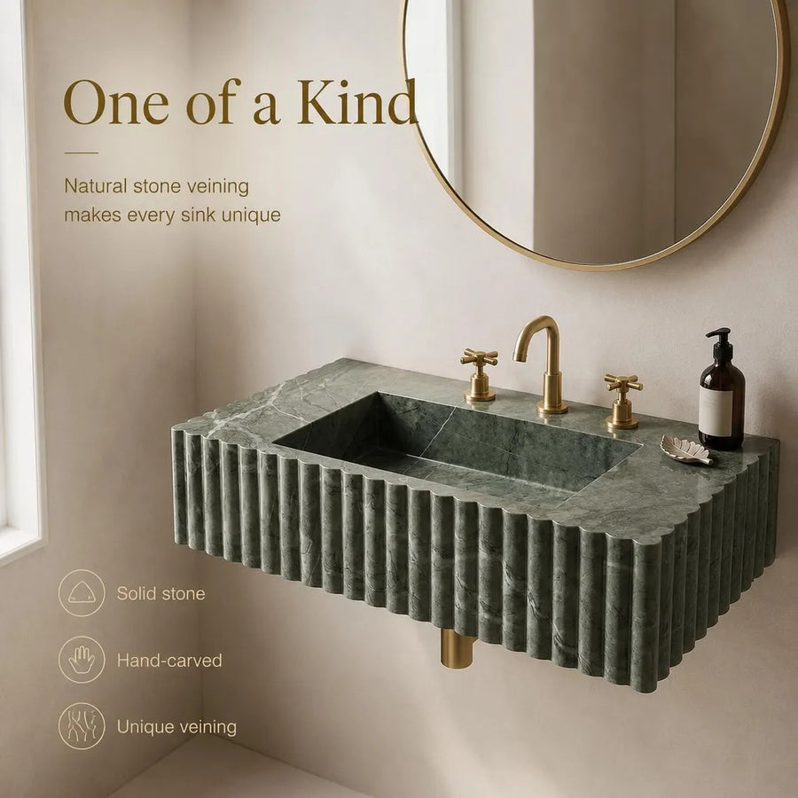 A floating rectangular bathroom sink made of dark green fluted stone, paired with a gold faucet and handles, shown in a styled bathroom setting with a round mirror and text overlays highlighting its features.