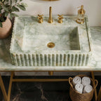 Marble sink with gold fixtures in a bathroom setting