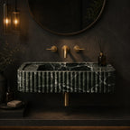 Green Levanto marble fluted sink in a dark moody bathroom with brass fixtures