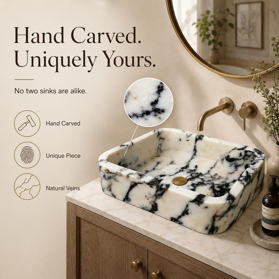 Black and white marble sink with brass faucet and running water on a beige stone countertop