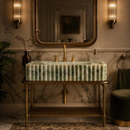 A luxury bathroom vanity featuring a ribbed green marble sink basin with a gold faucet and brass stand, set against a marble wall with a large gold-framed mirror.