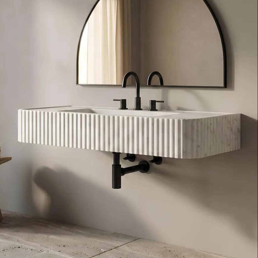 Bathroom with a modern sink and round mirror on a neutral wall.