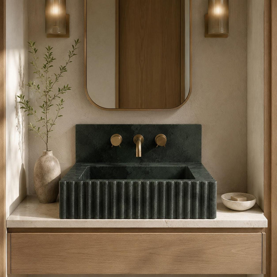 Green marble fluted sink on a light countertop with brass faucet and round handles