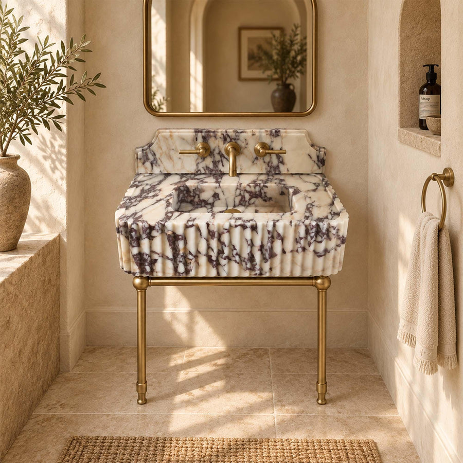 Calacatta Viola fluted vanity sink with white and purple veining on slender brass legs, side view