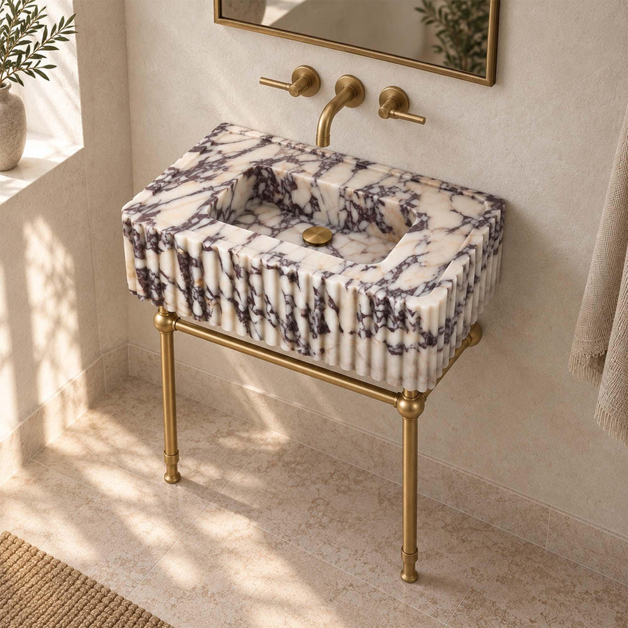 Calacatta Viola fluted console sink with wall-mounted brass faucet and two handles above the basin