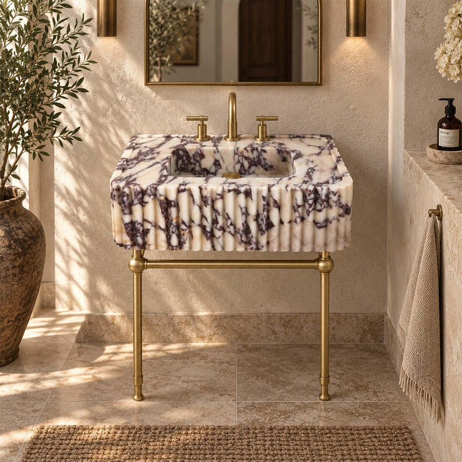 Calacatta Viola marble fluted sink with deep purple veining on a brass stand with two front legs