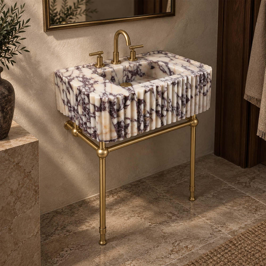 Calacatta Viola fluted marble bathroom sink on a four-leg brass stand with brass faucet and handles