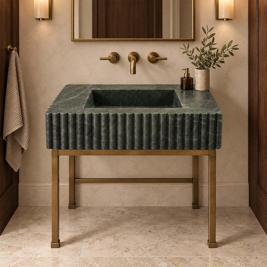 Close-up of hand-carved scalloped rim and vertical fluting on a green marble bathroom sink