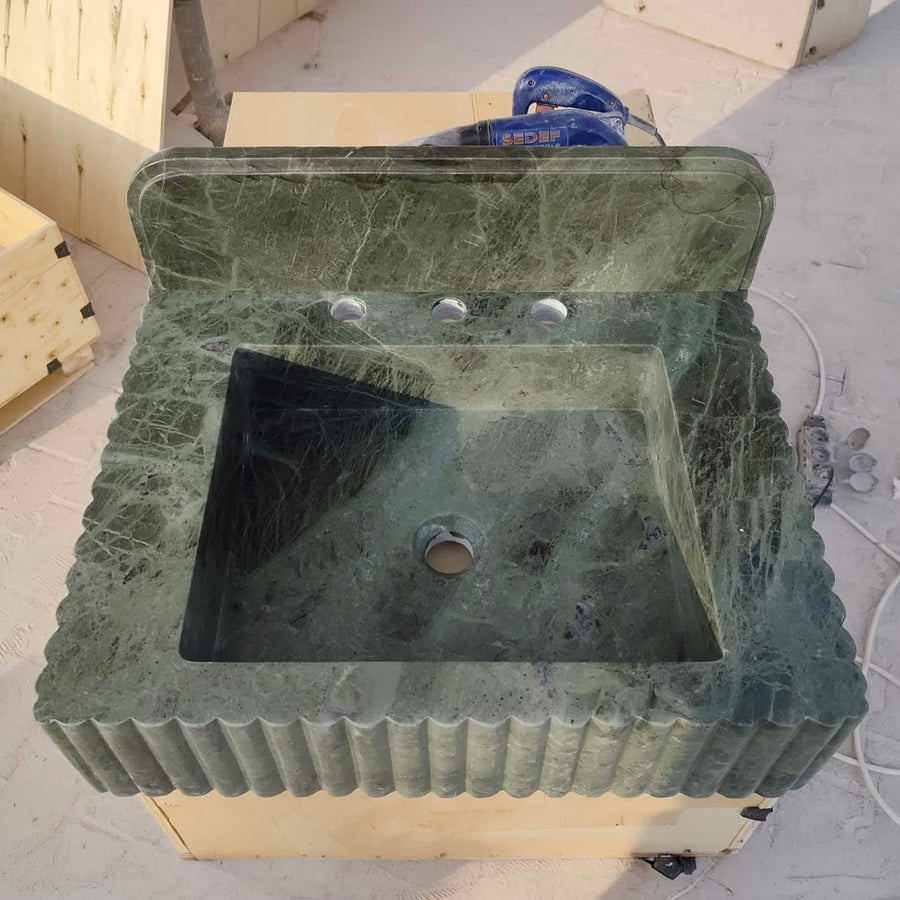 Rectangular green marble bathroom sink with high backsplash, fluted front and three centered faucet holes, top view