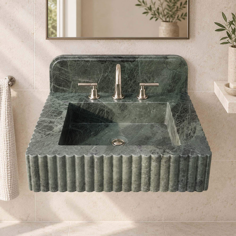 Hand-carved green marble washbasin with rounded backsplash on a warm plaster wall