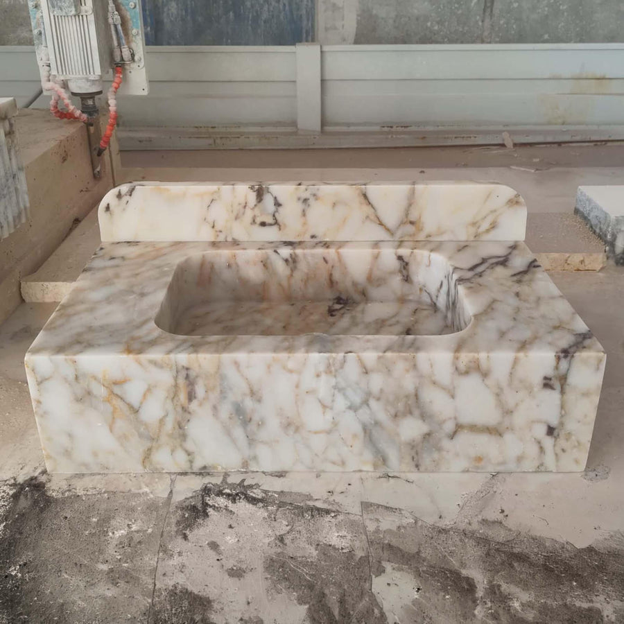 Side view of a solid Calacatta Gold smooth console sink