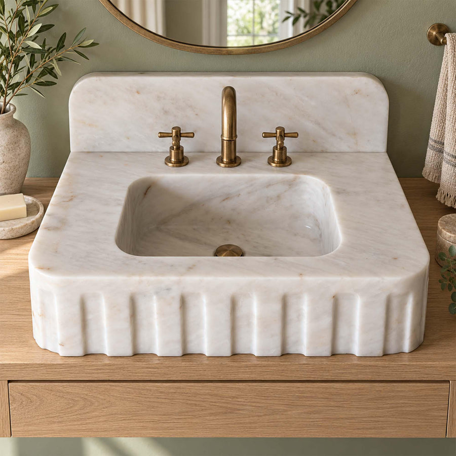 Angled view of a handcrafted Carrara White bathroom sink
