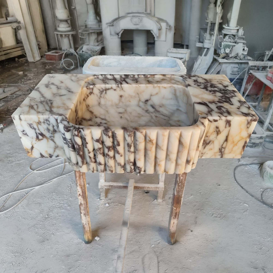 Front view of a hand-carved Calacatta Viola fluted apron console sink