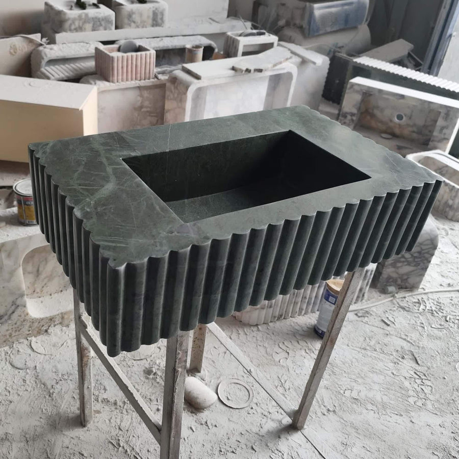 Scalloped edge green marble vanity basin with vertical fluting, wall-mounted in a powder room