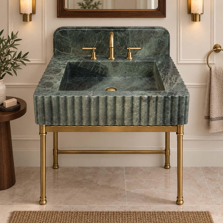 Green marble backsplash sink with fluted apron and brass widespread faucet, angled view