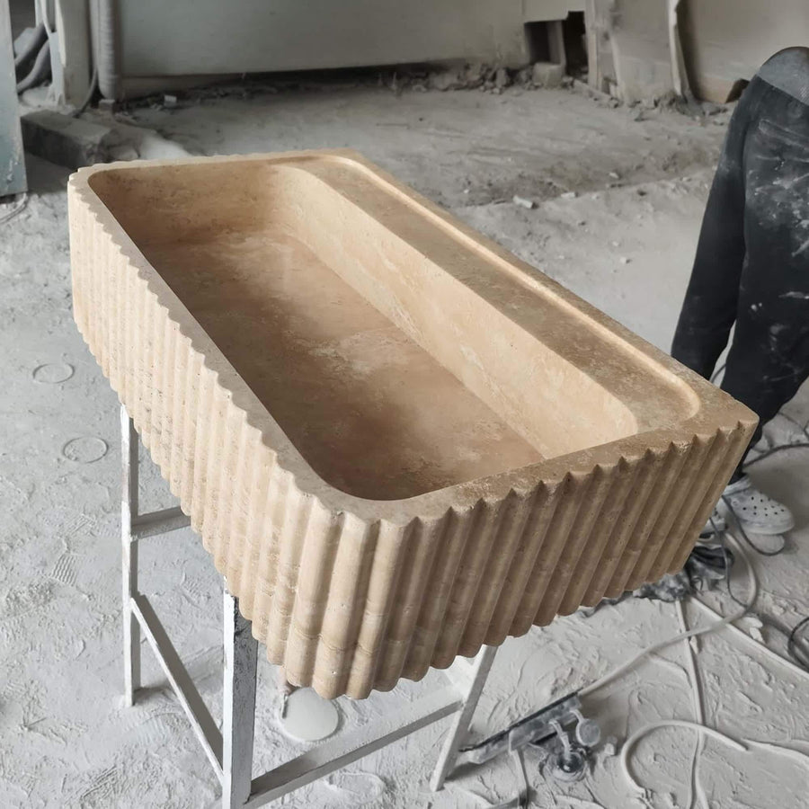 Beige travertine fluted console sink styled in a designer powder room