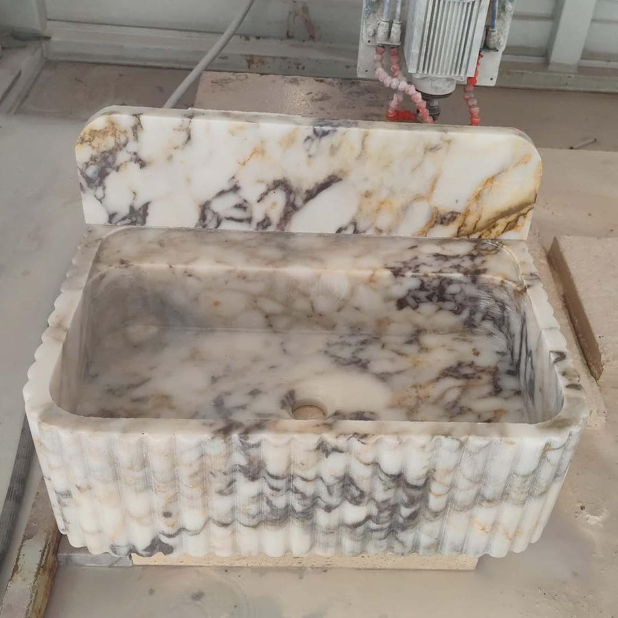 Side view of a solid Calacatta Gold fluted vanity sink
