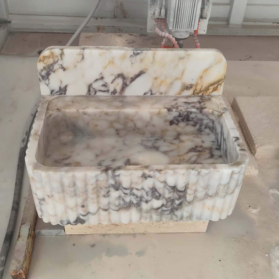 Calacatta Gold fluted vanity sink showing the drilled faucet holes