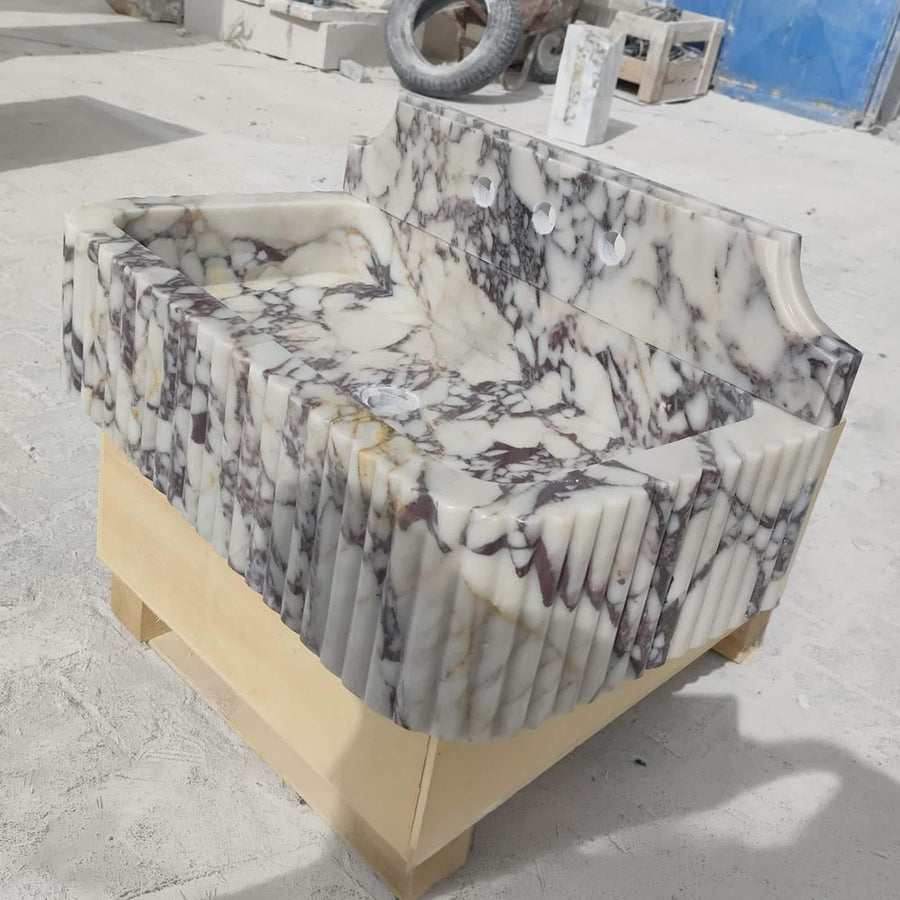 Front view of a hand-carved Calacatta Viola fluted console sink