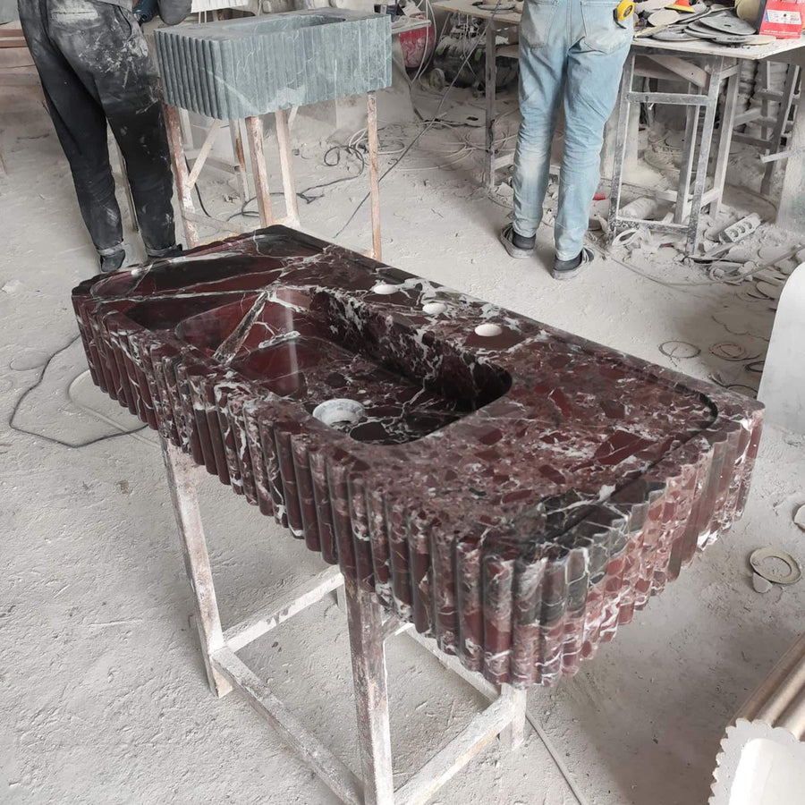 Front view of a hand-carved Rosso Levanto fluted console sink