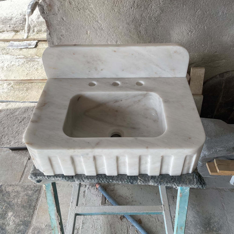 Front view of a hand-carved Carrara White fluted vanity sink