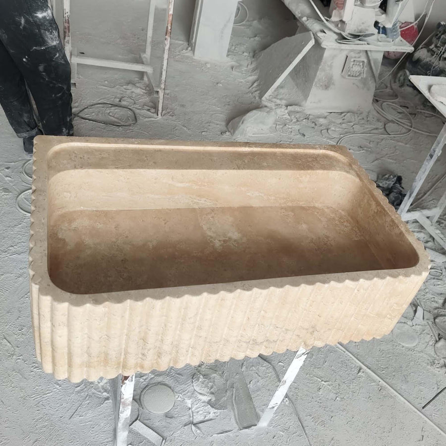 Side view of a solid Beige Travertine fluted console sink